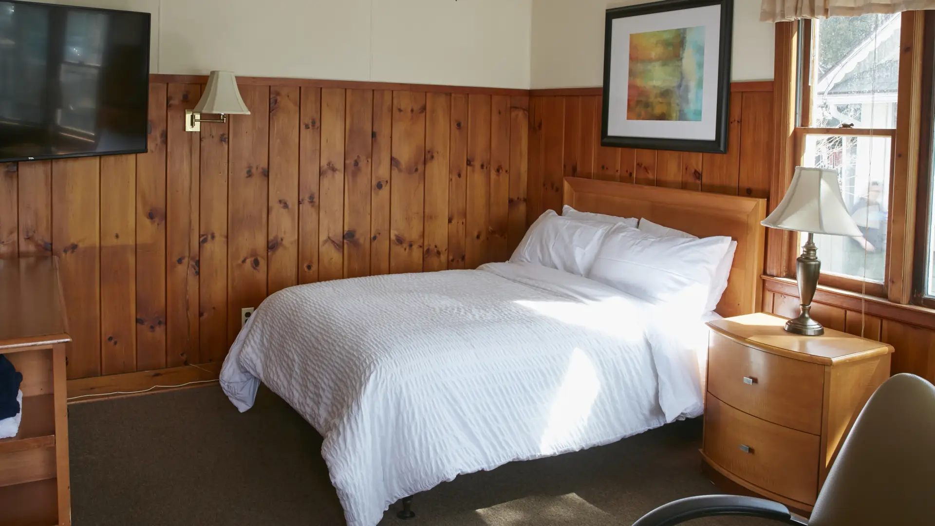 Plush white linens on a queen bed in a wood paneled room at The Ashley.