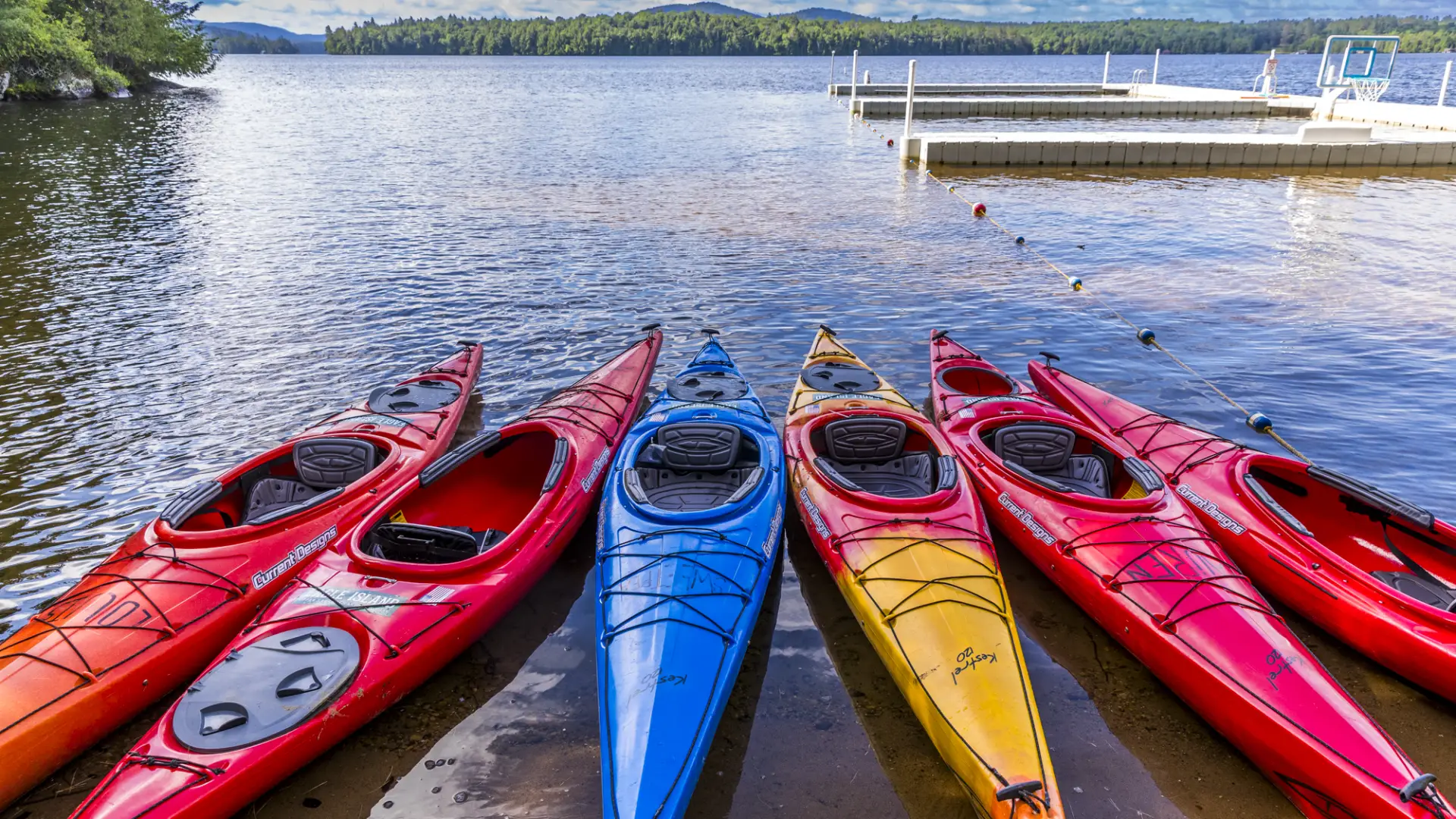 Brightly colored kayaks on the shore of the lake.