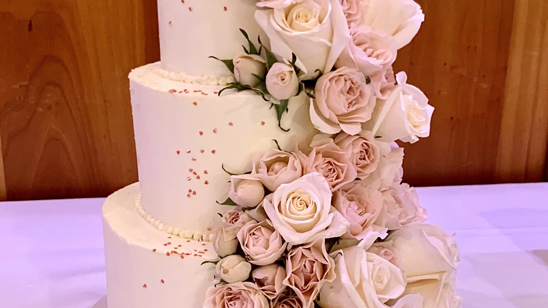 Pink roses flowing down a three tiered cake like a waterfall.