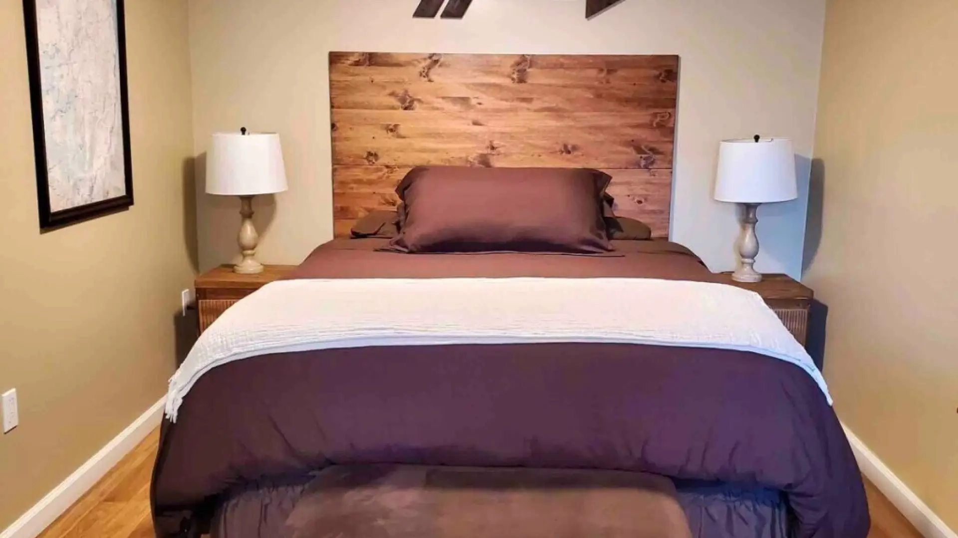 The primary bedroom with a large bed, wooden headboard and a wooden arrow decor on the wall.
