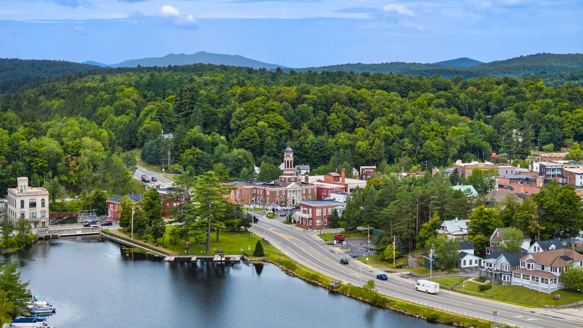 A backed up aerial view of the clock tower at the Harrietstown Town Hall and proximity to Lake Flower