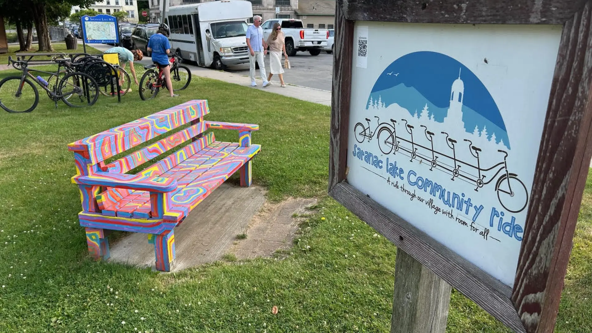 colorfully painted bench beside a community bike ride sign 