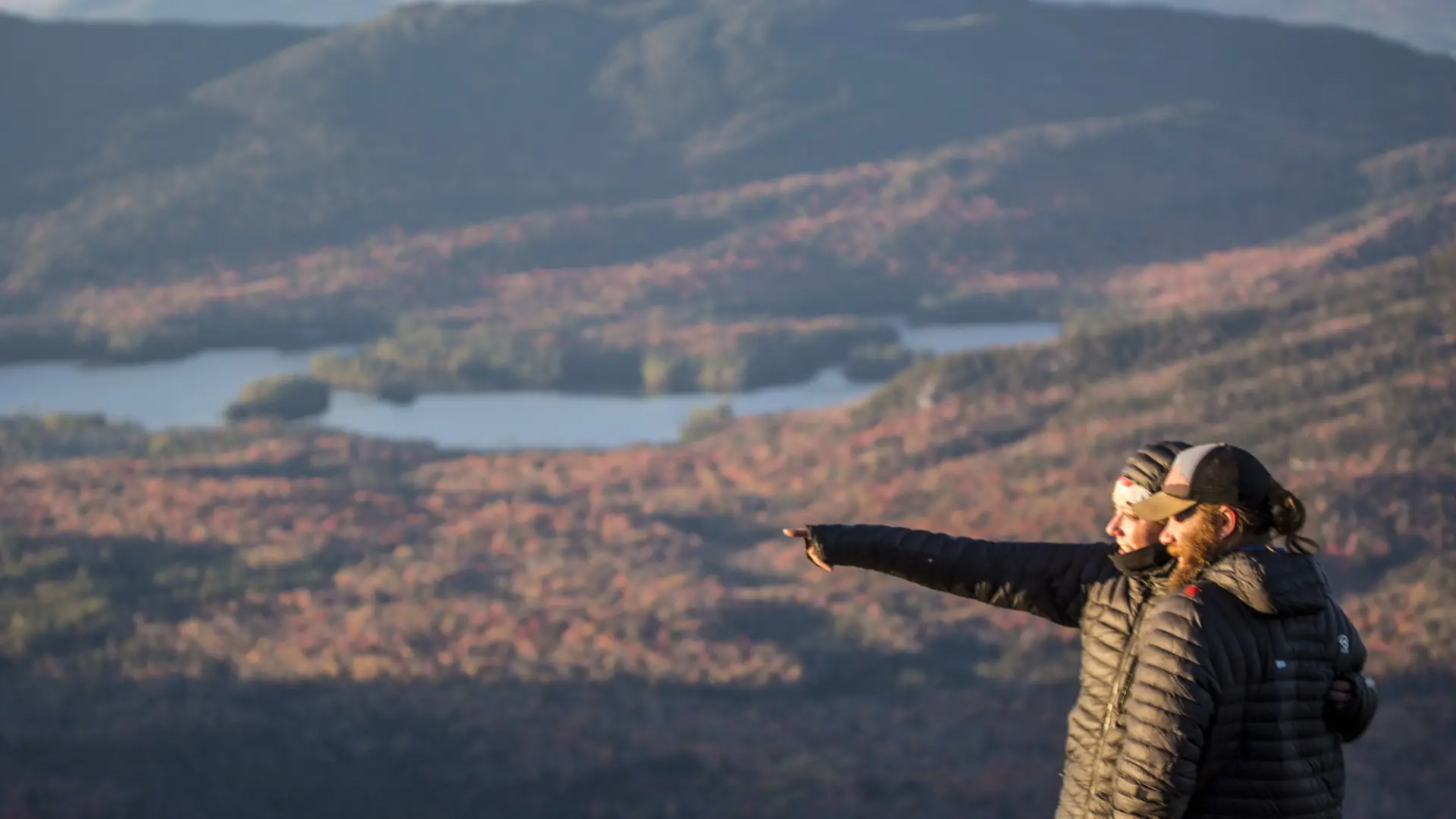 Hikers pointing at things from top of mountain