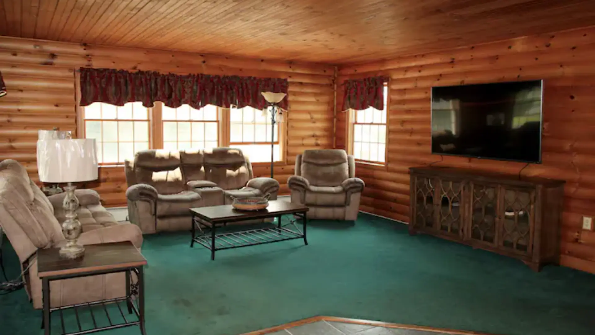 A great room with green carpet and wood paneled walls.
