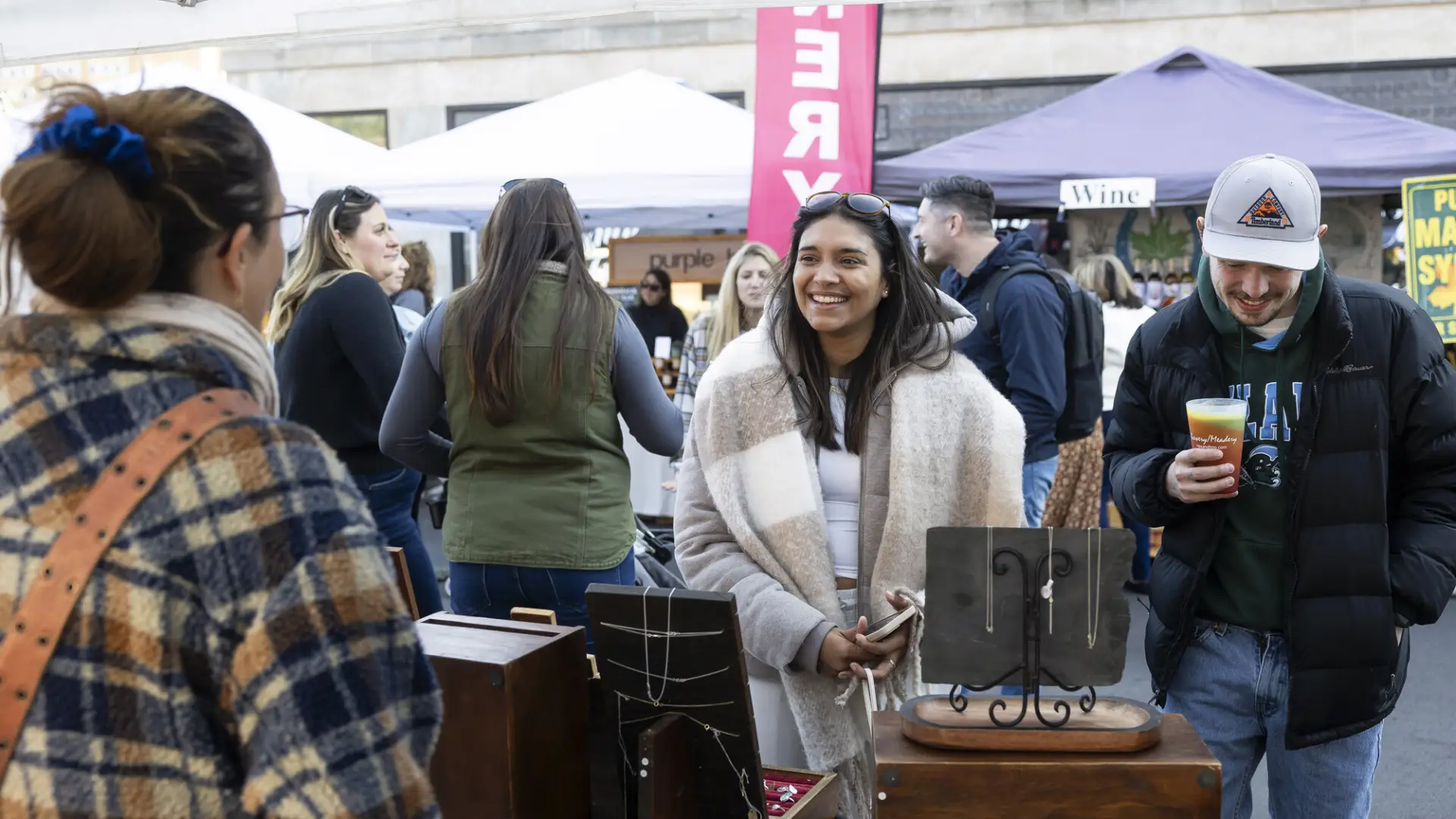 A man and woman visit a booth at a farmers market. 