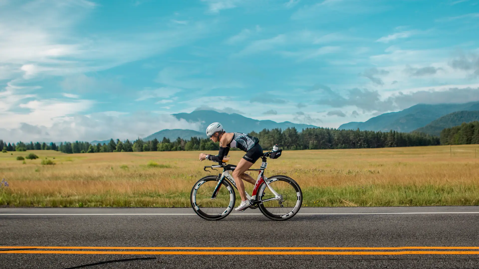 ironman biking on flat road past mountain view