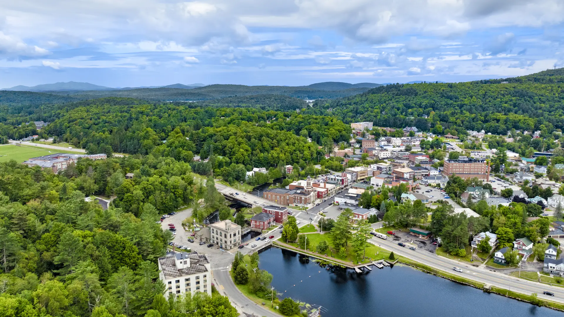 A backed up aerial view of the clock tower at the Harrietstown Town Hall and proximity to Lake Flower