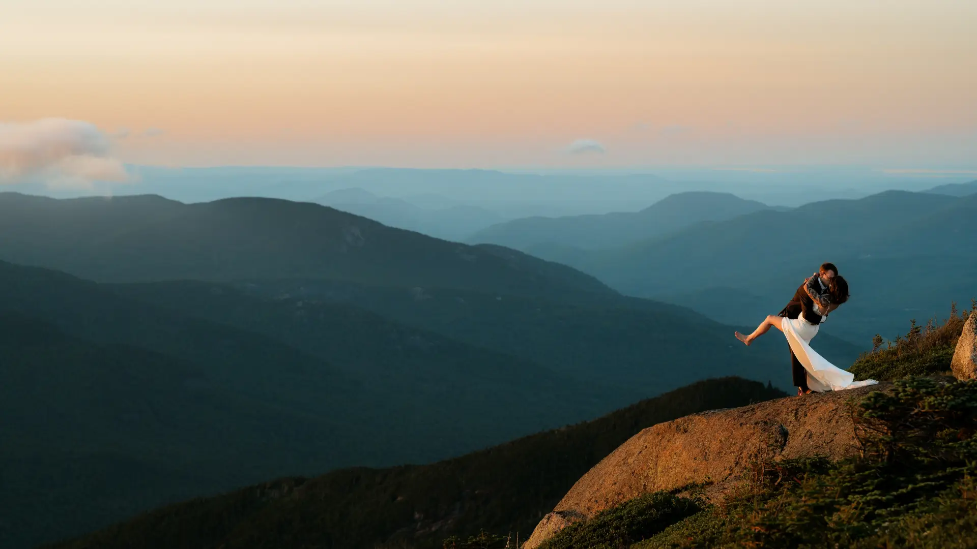 A dip and a kiss of bride and groom on top of a mountain