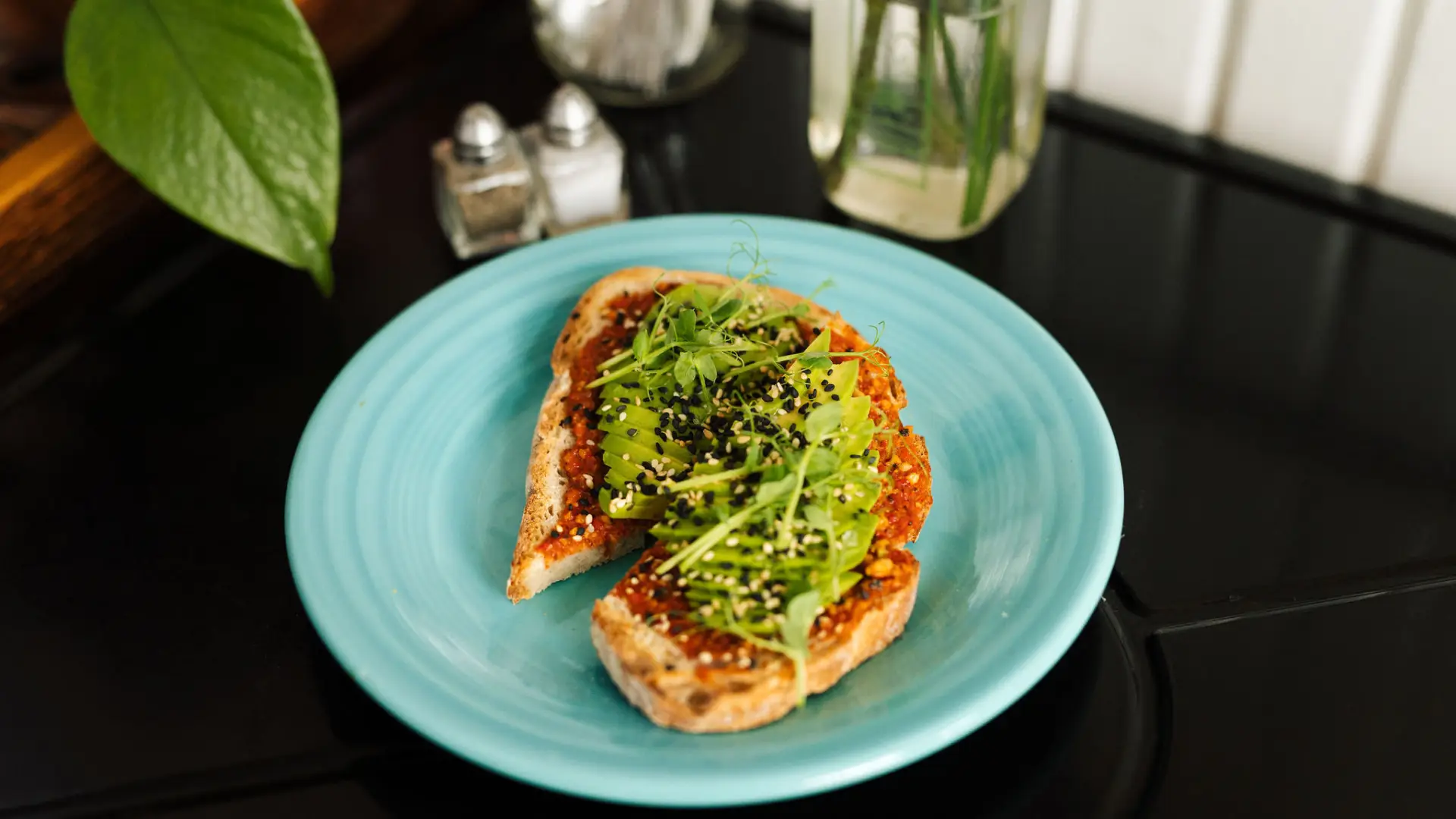 Avocado toast with sprouts on a colorful plate.