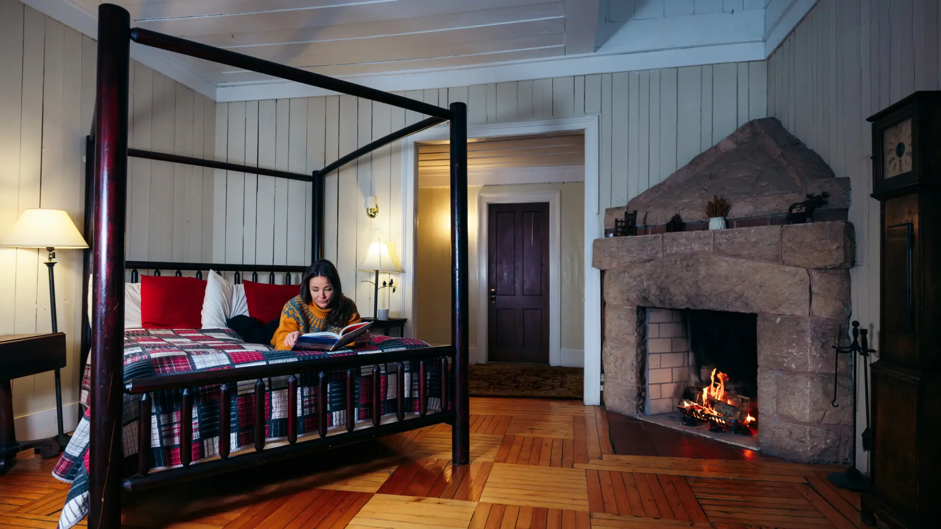 A woman reads a book on a bed in a cabin.