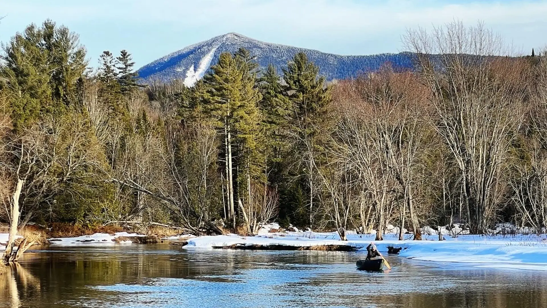 A view of a snow covered slide on a mountain from the water.