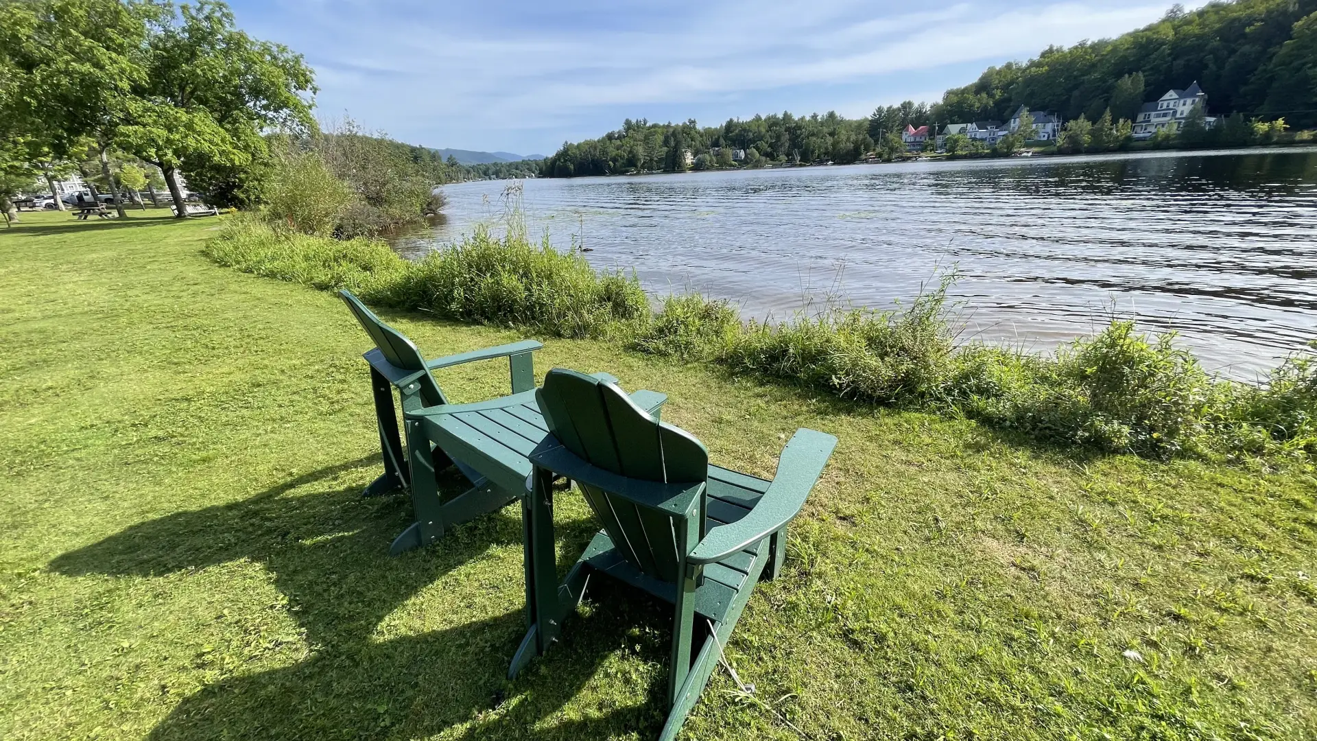 two adirondack chairs on the edge of a lake