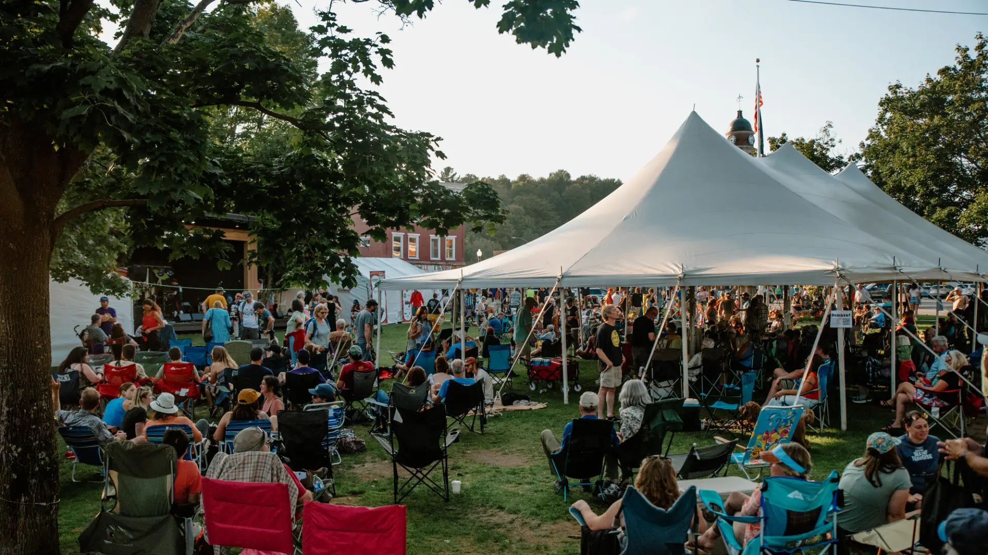 A huge crowd of people sit in lawn chairs to enjoy the music