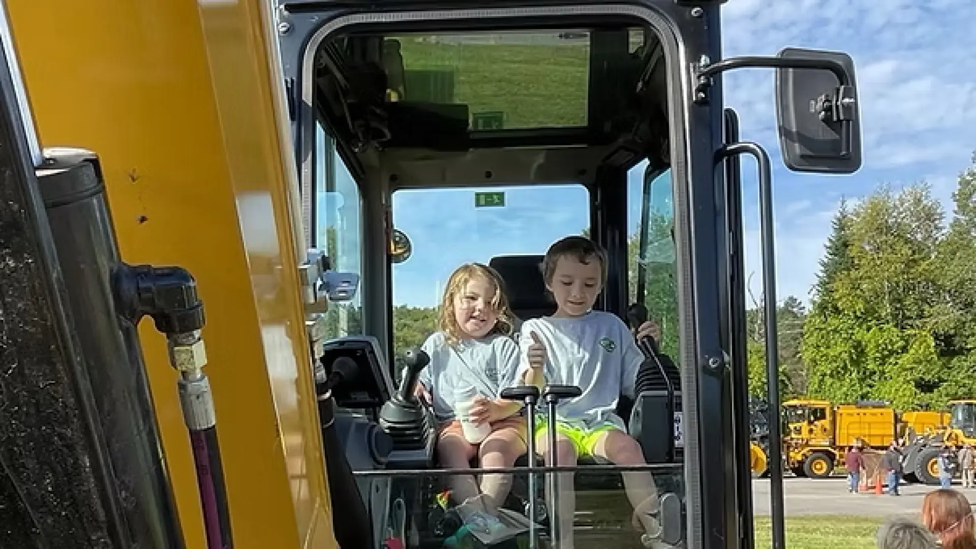 children sitting on yellow heavy machine