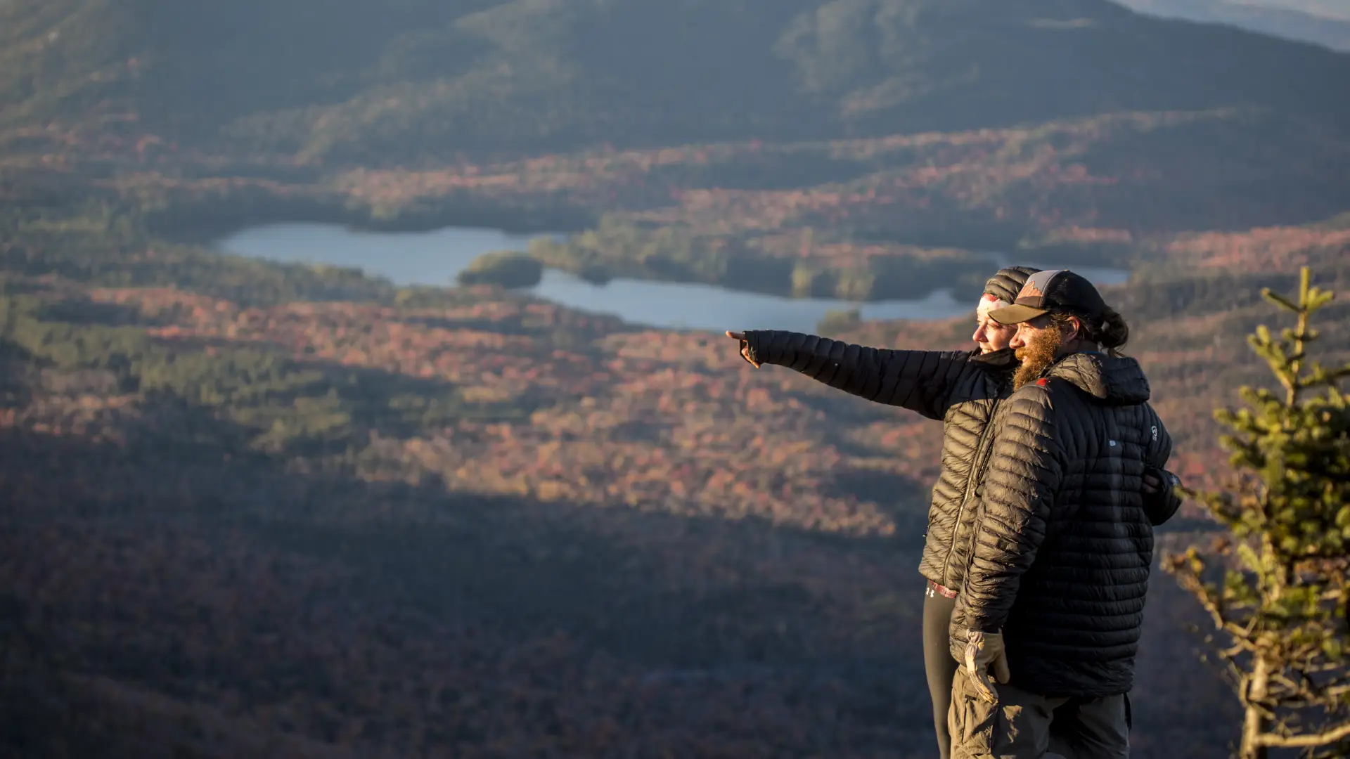 Two people enjoy a fall view from a mountain top