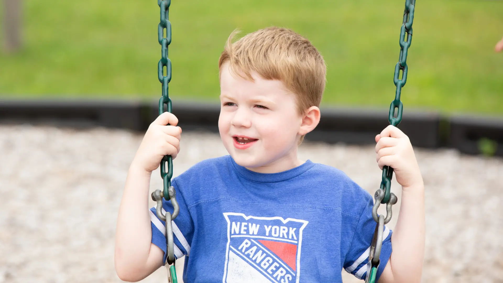 A young kid plays on a swingset