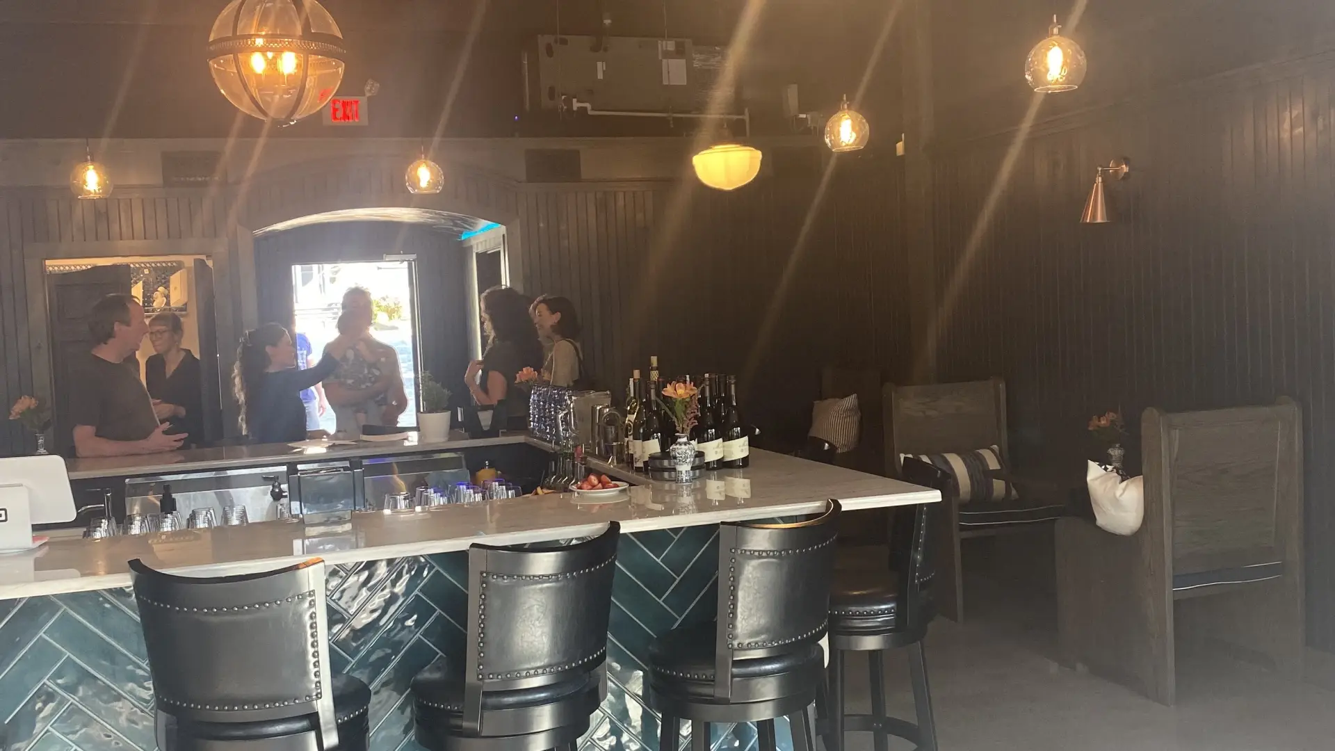 Looking into the bar area at the herringbone patterned deep green tiles on the bar