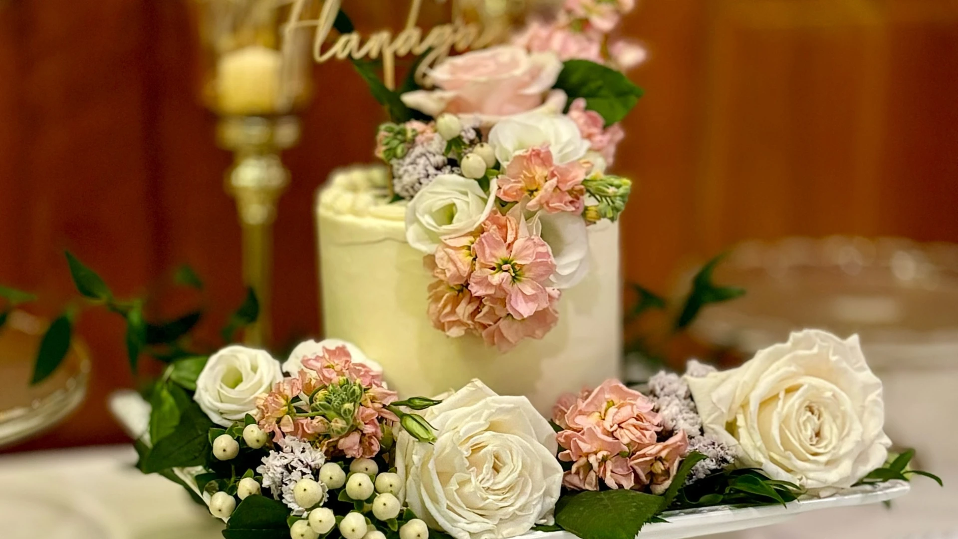 A single tier cake decorated with white and pink flowers.