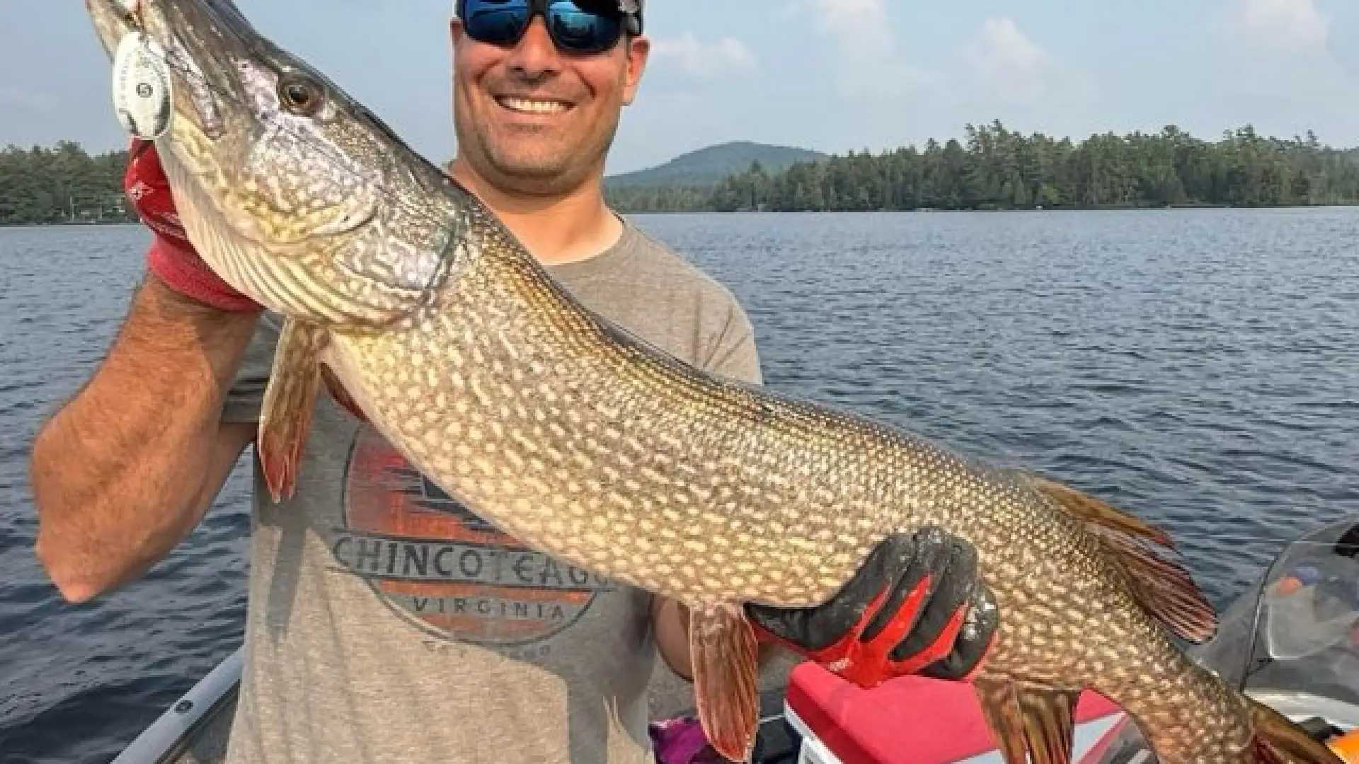 A smiling man holds a huge pike