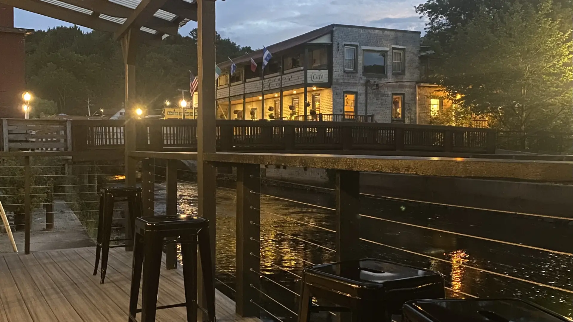 The covered terrace by the river illuminated at dusk