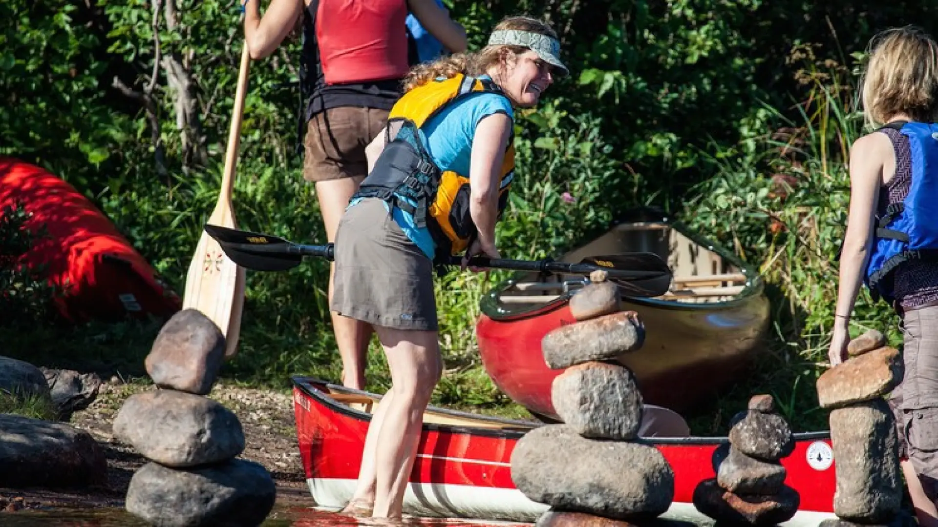 A smiling woman in a life jacket ready to board a boat.