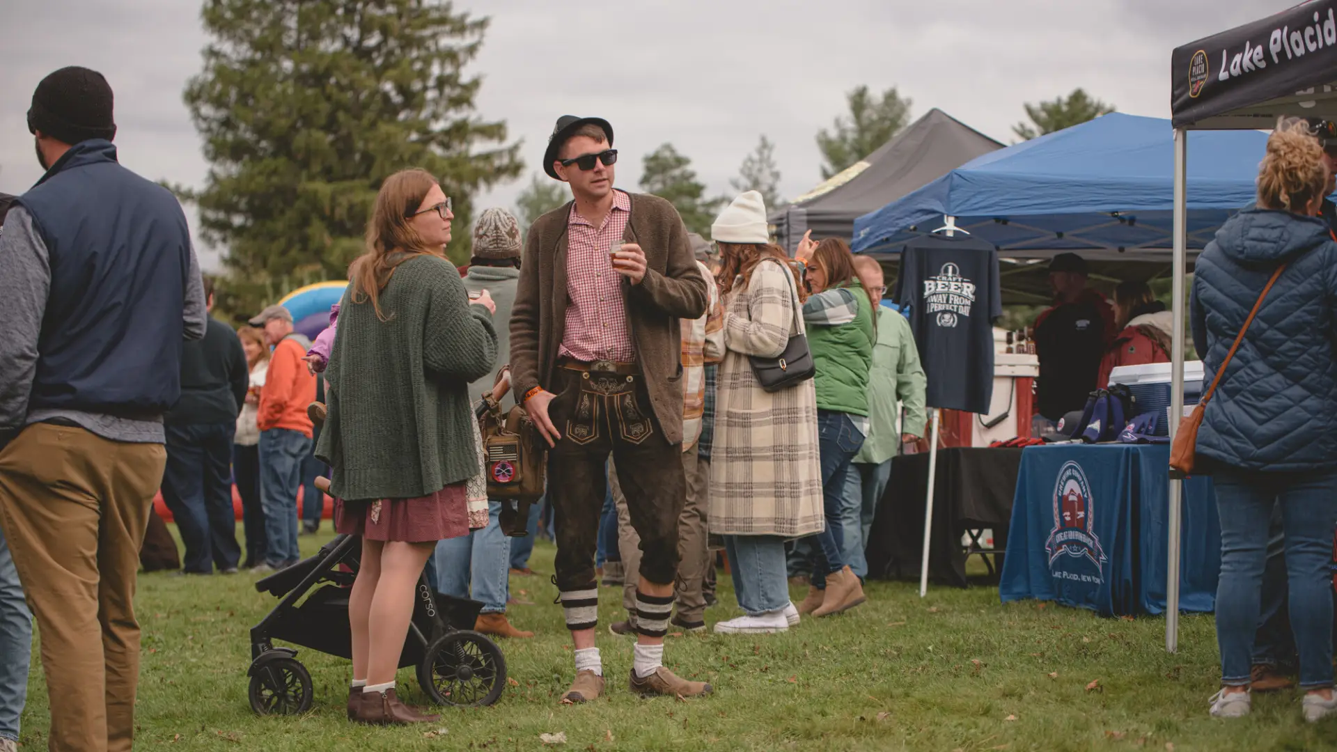 a man in german traditional clothes enjoys a fall market. 