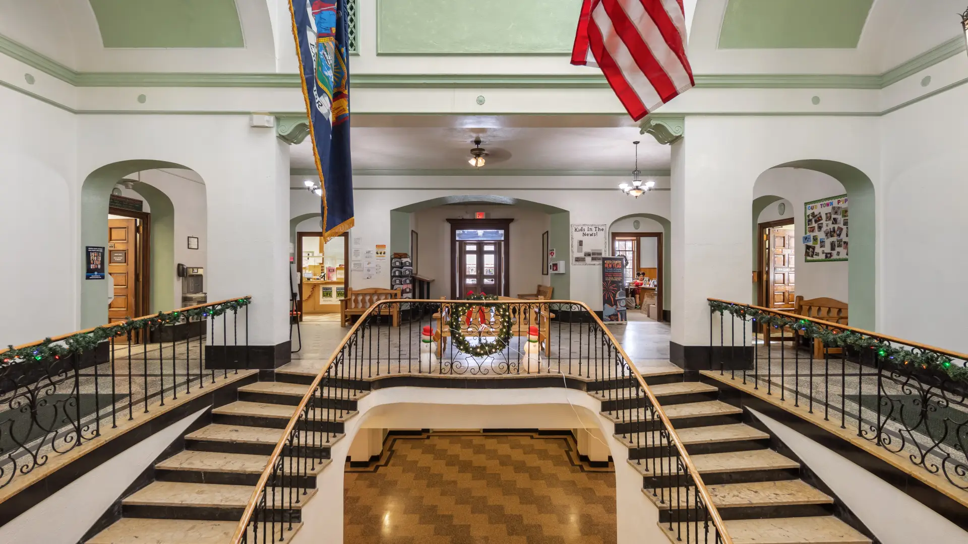 A grand, double sided staircase with stone steps and sky lights at the Harrietstown Town Hall.