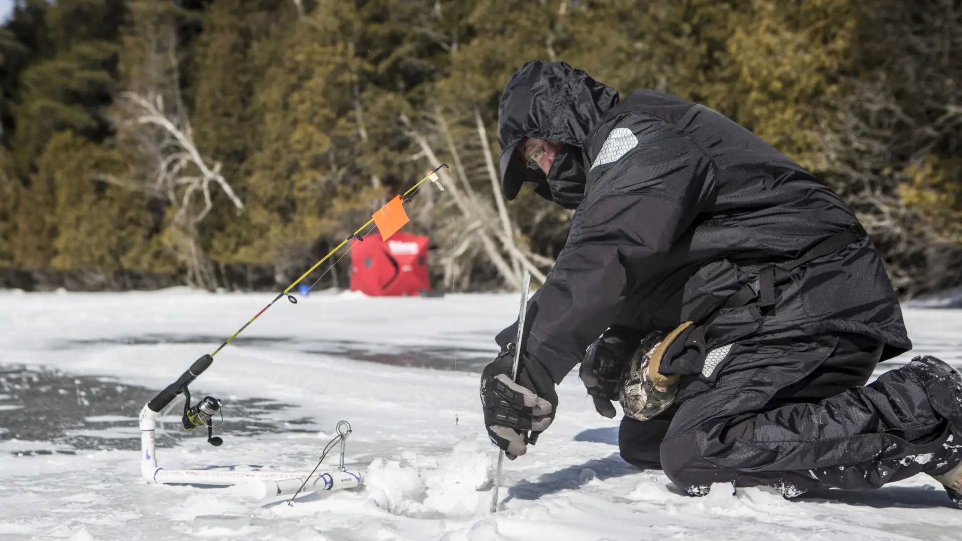 Someone cutting a hold in the ice for fishing