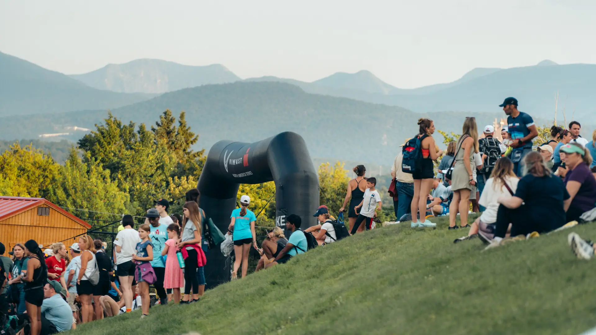 Spectators on hill above Ironman finish with mountains in background