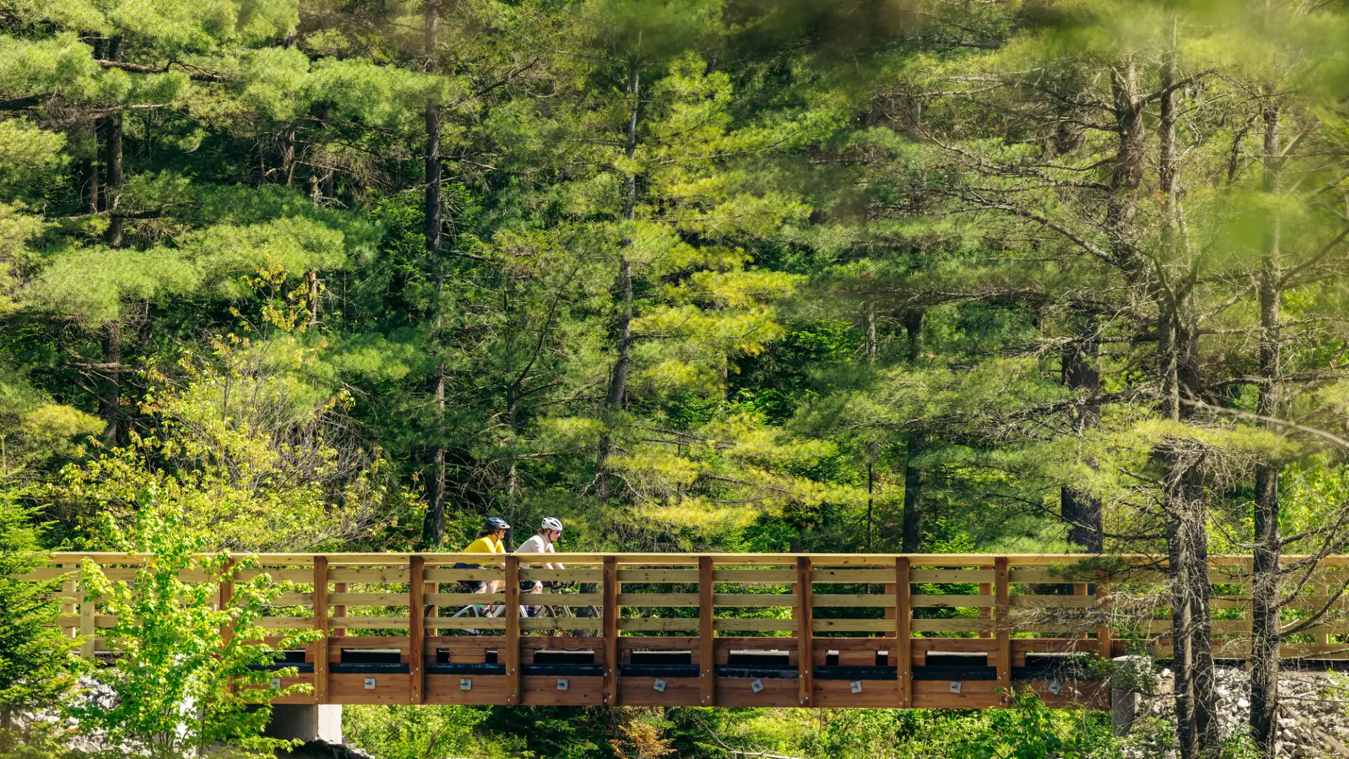Two people cycle across a bridge