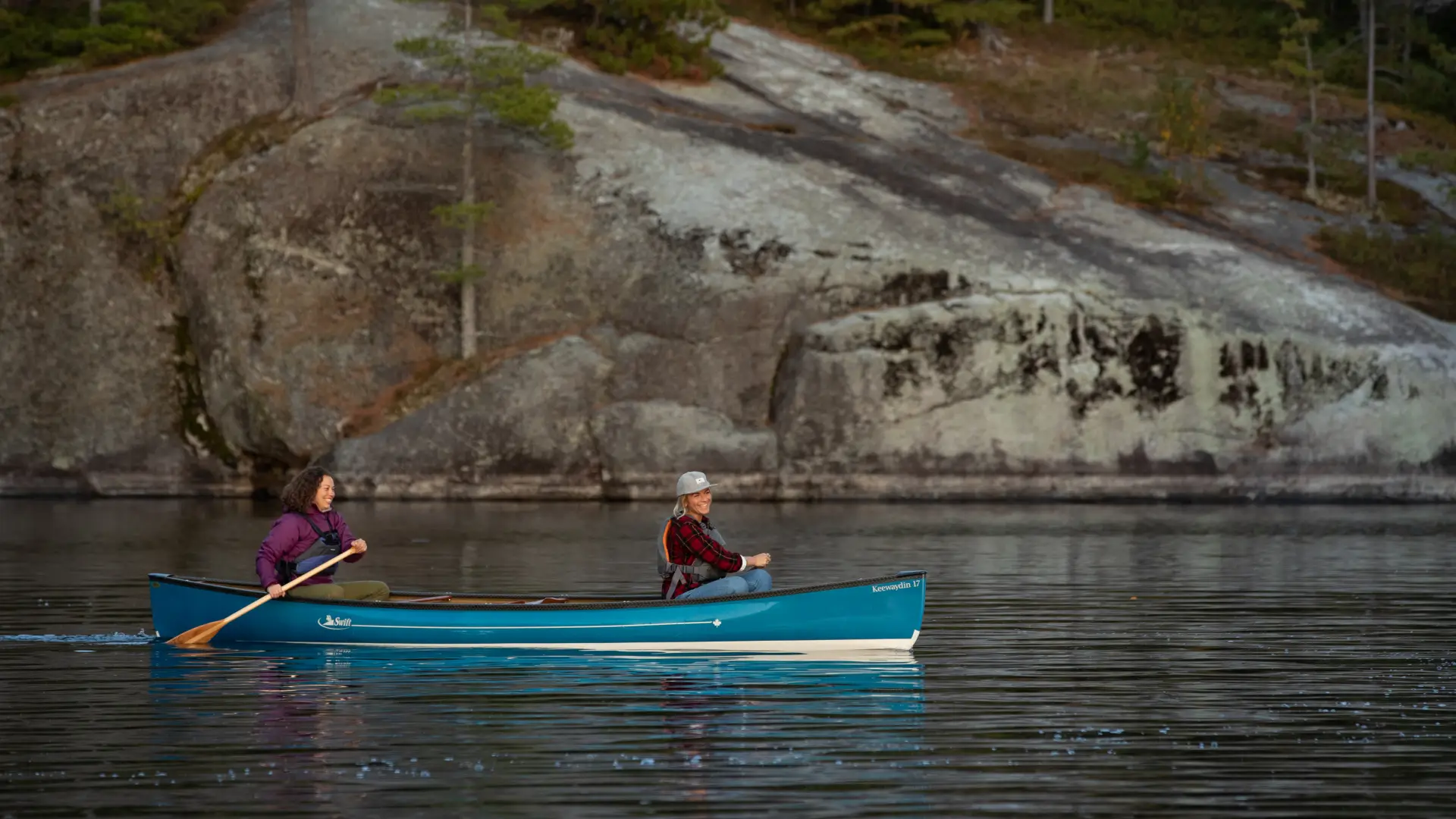 Two people paddle in a blue canoe on Lower Saranac Lake.