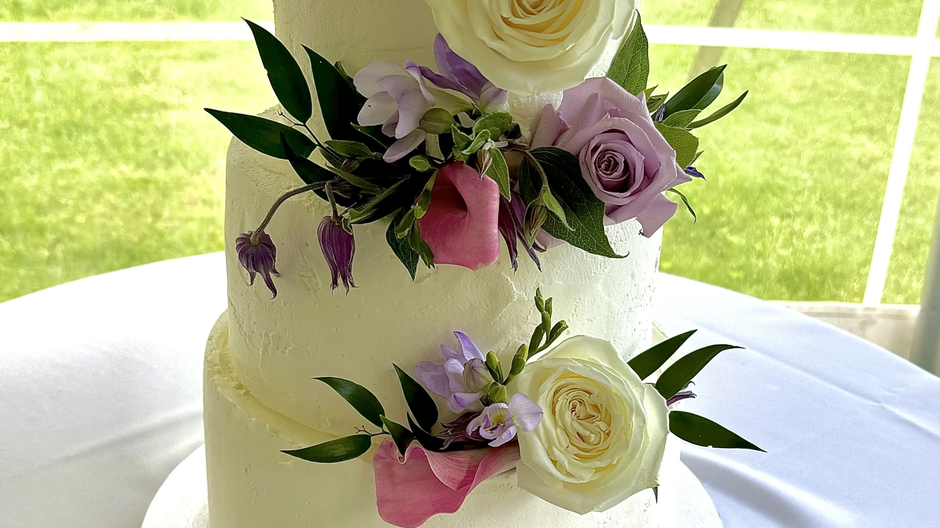 A three tiered cake decorated with pastel colored roses.