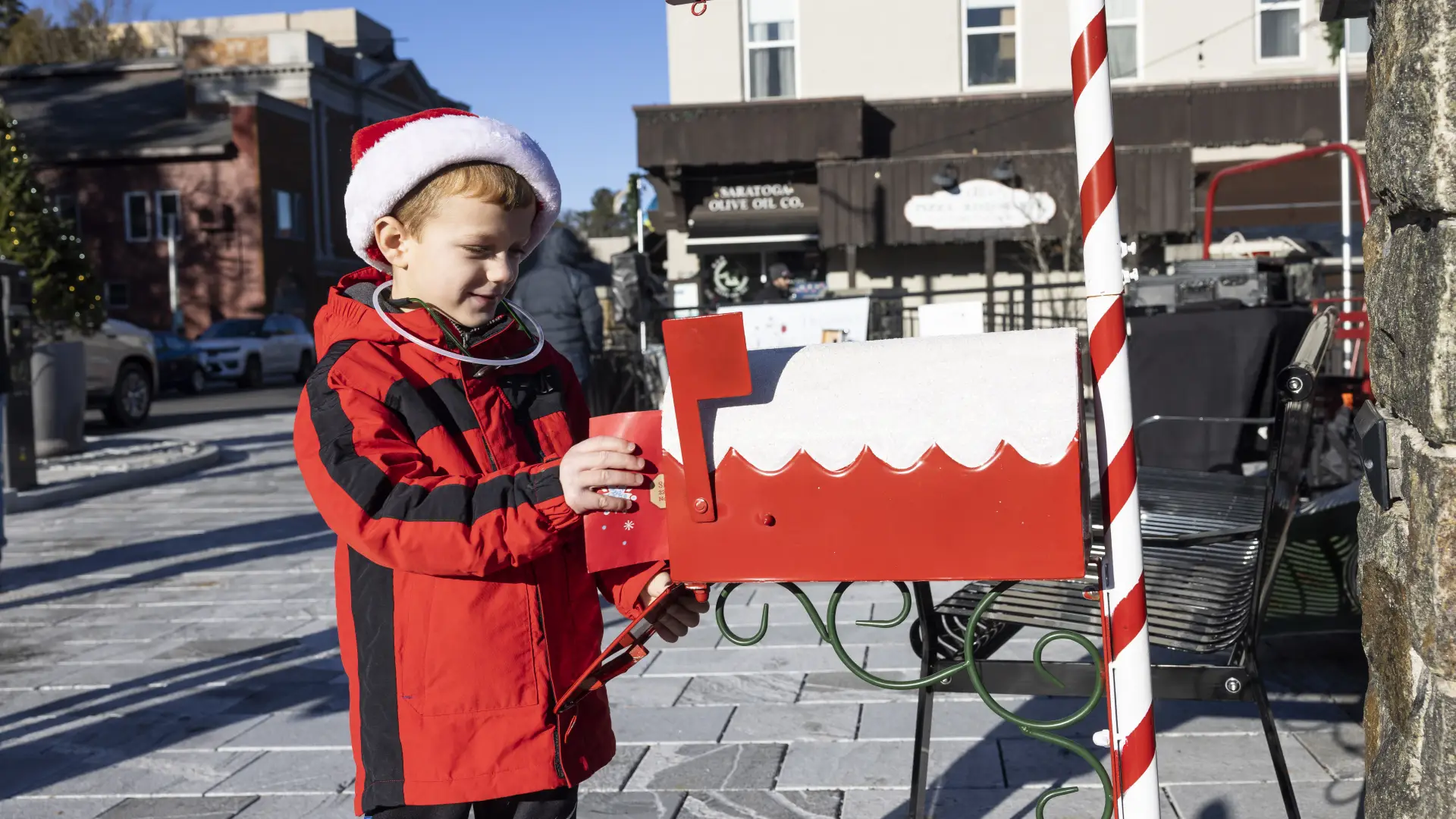 Image of a child putting his letter to Santa into a mailbox.