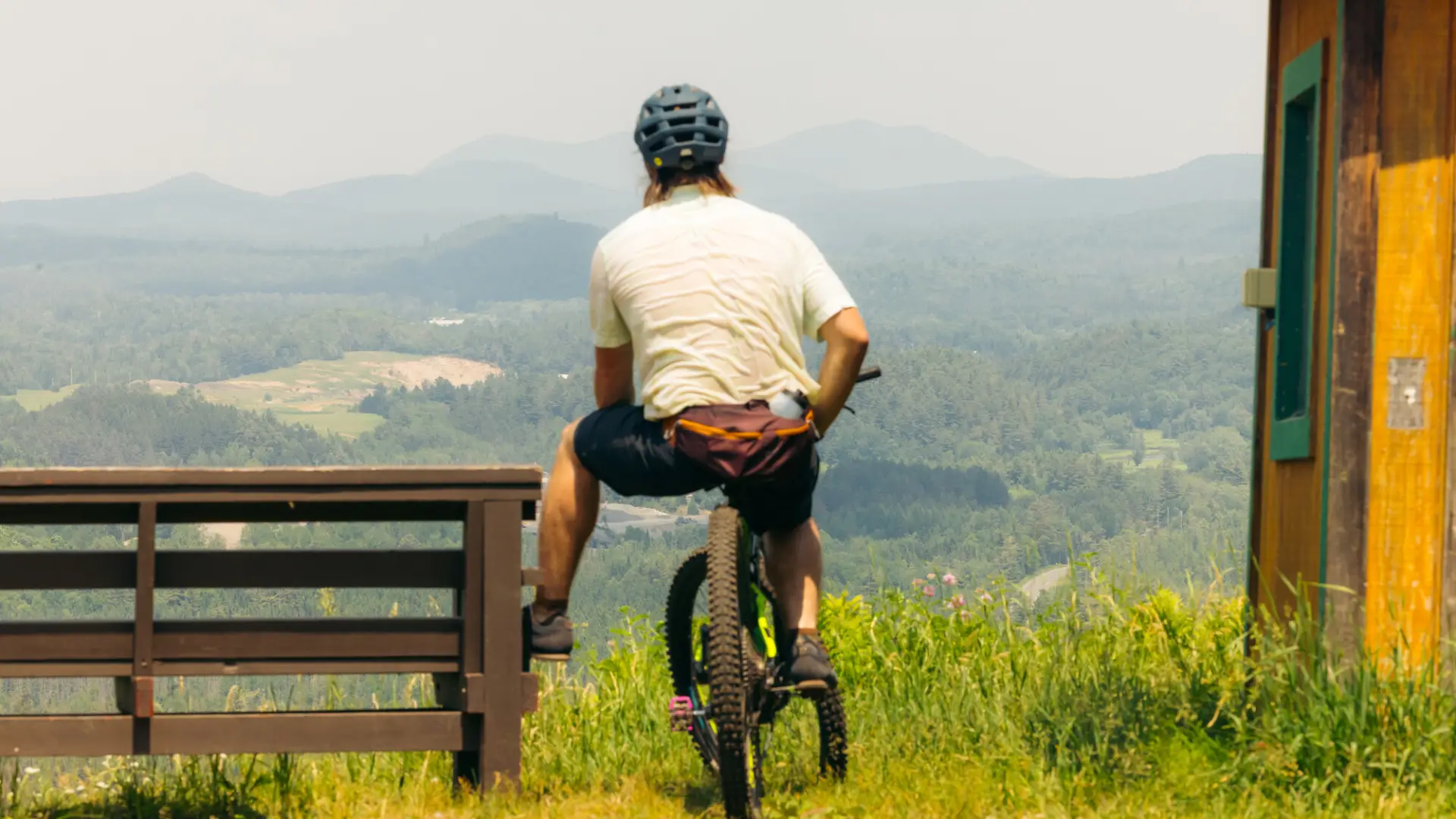 A mountain biker enjoys mountain views up a summit bench