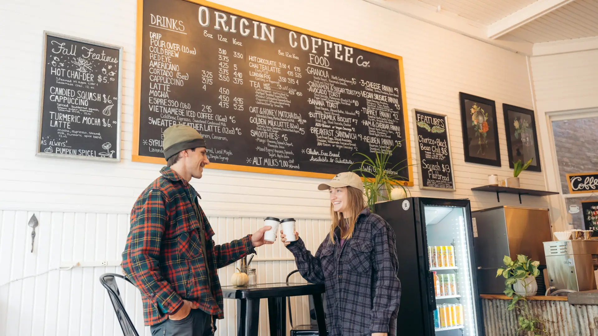 A man and woman enjoy coffee at a brightly lit coffee shop. 