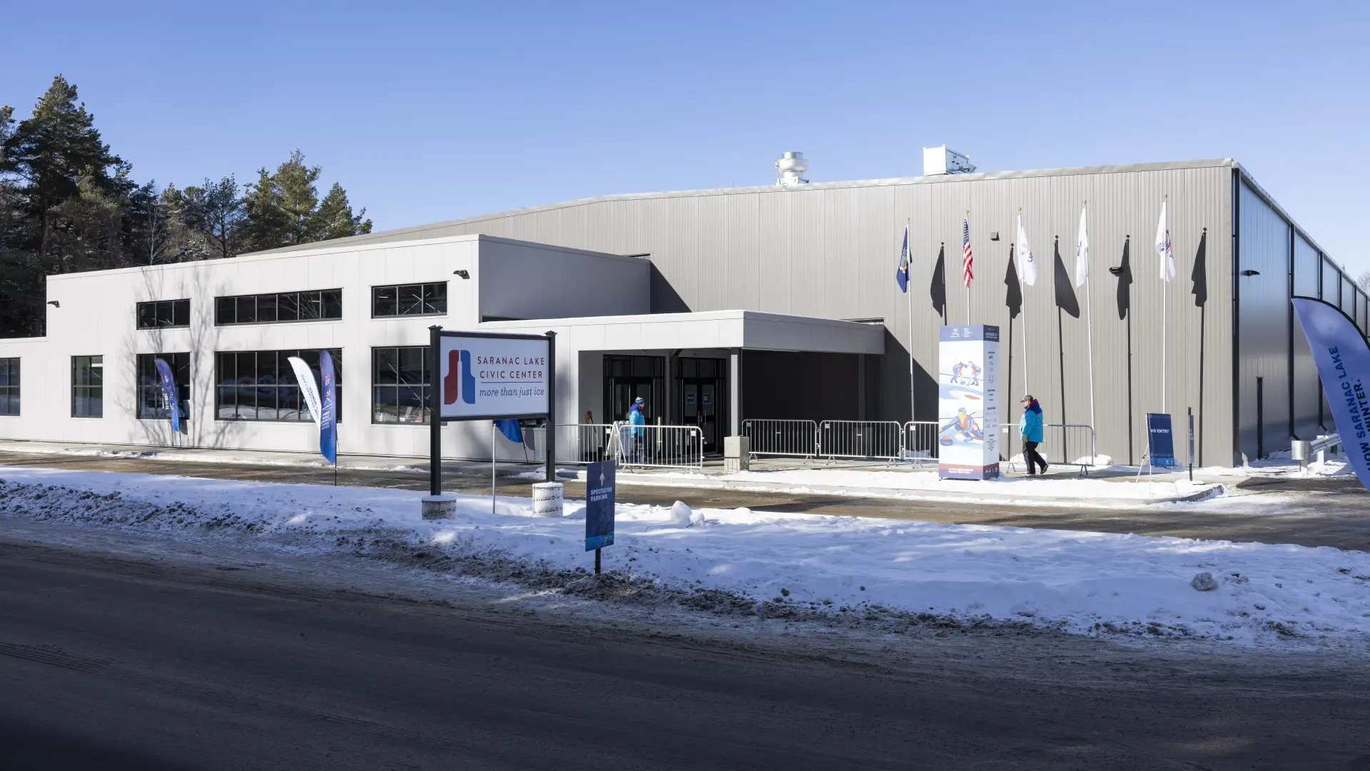 A snowy exterior of the Saranac Lake Civic Center and sign.