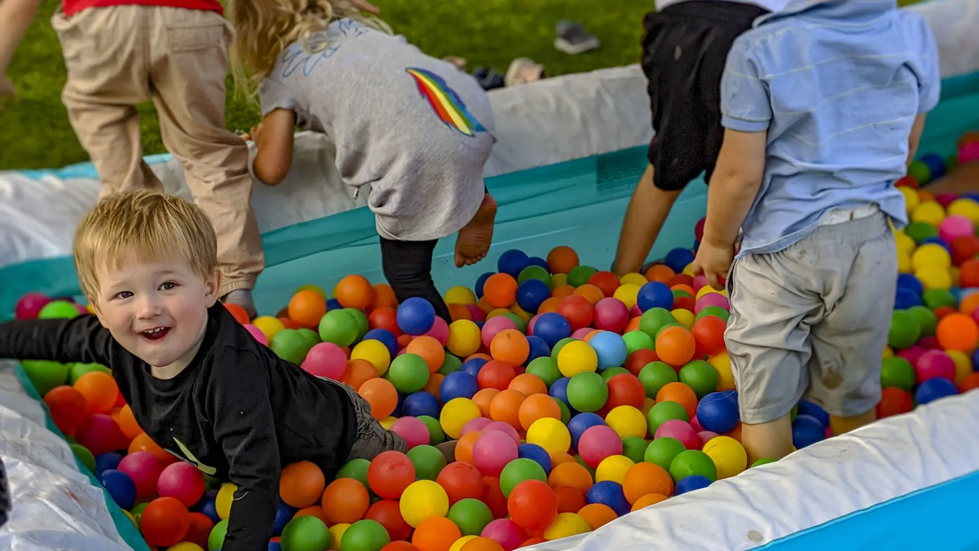 Little ones enjoy a ball pit set up in an inflatable swimming pool