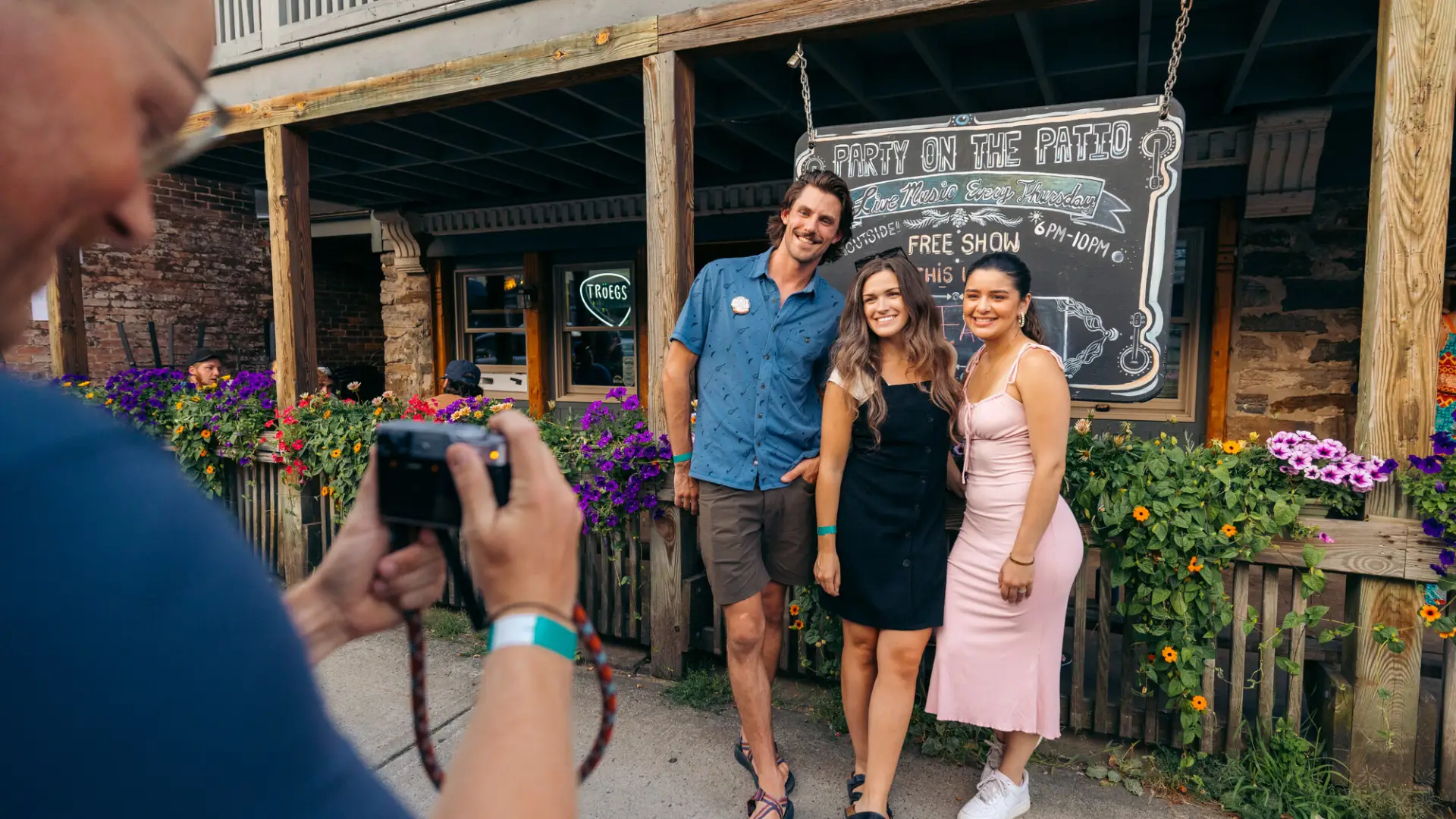 A group of friends smile and pose for a picture in front of a restaurant. 