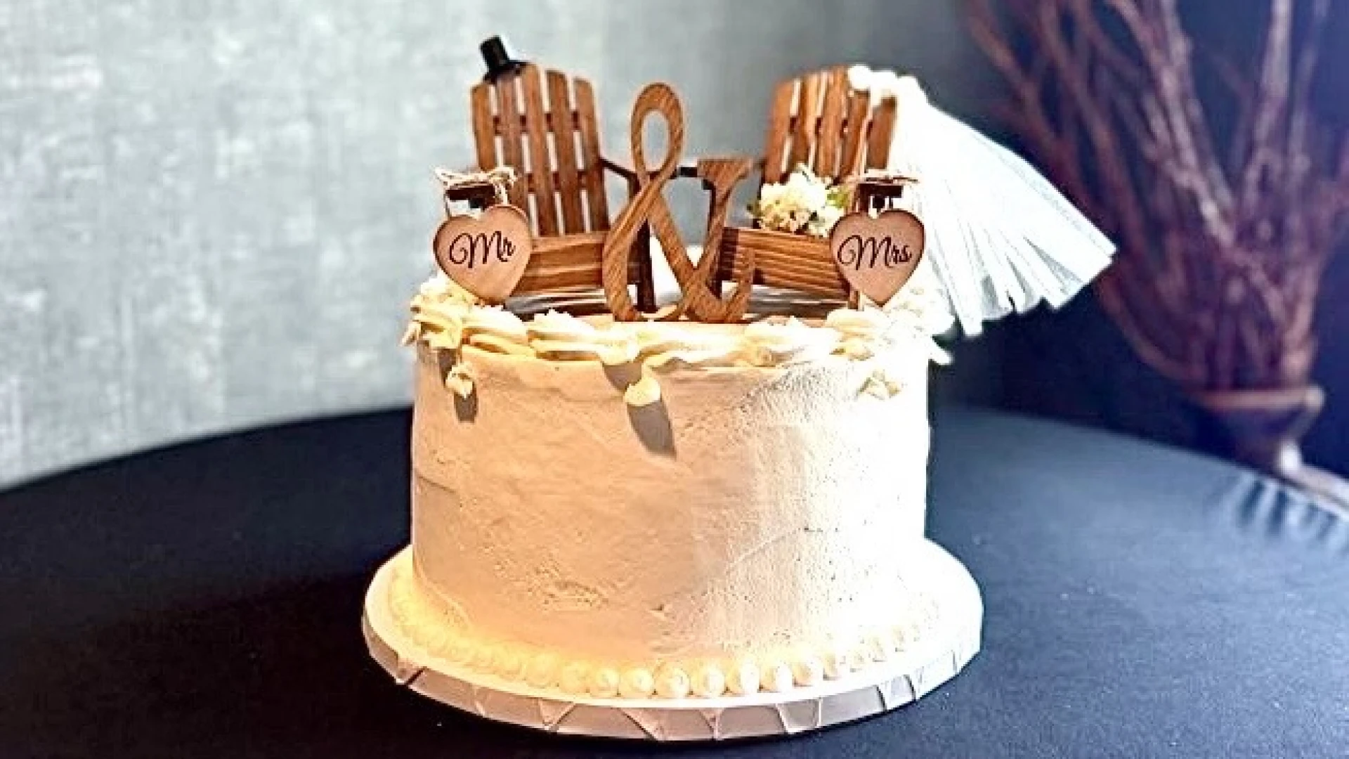 A single tiered cake topped with bride and groom styled adirondack chairs.