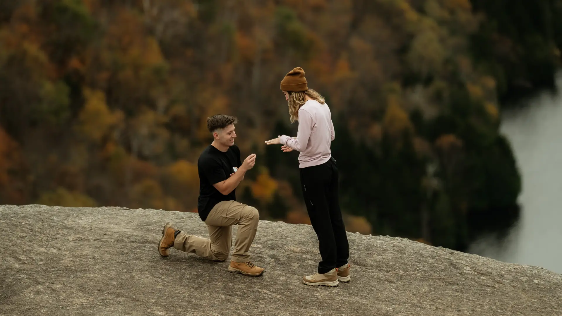 Mountain top engagement with a man on one knee overlooking a lake