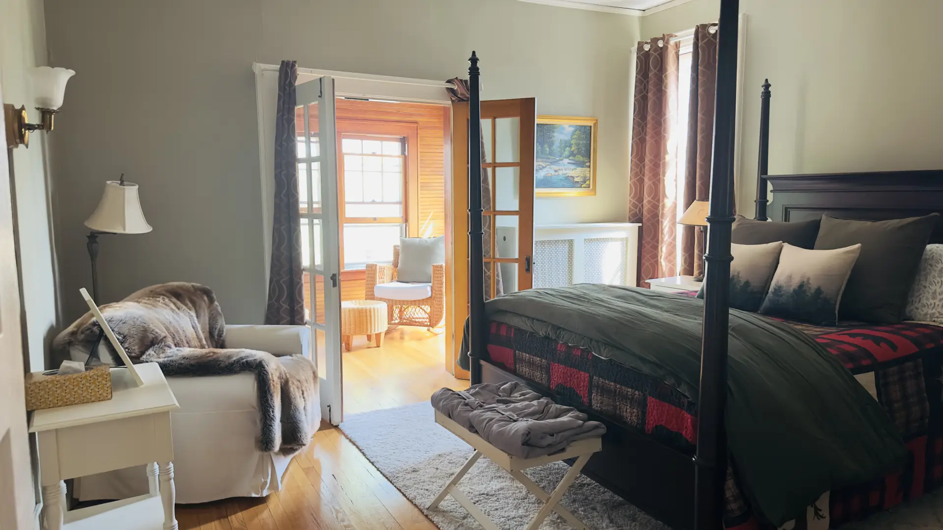 A dark 4 post bed with adirondack themed bedding and bright french doors calling you through.