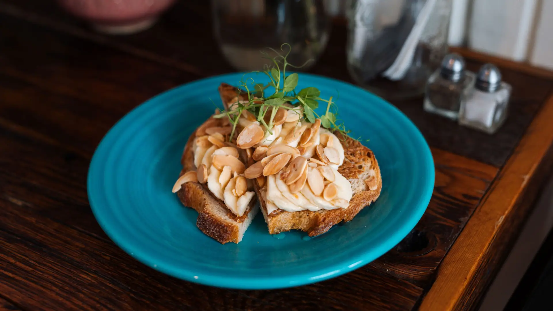 Sliced banana and peanuts on toast on a blue plate.