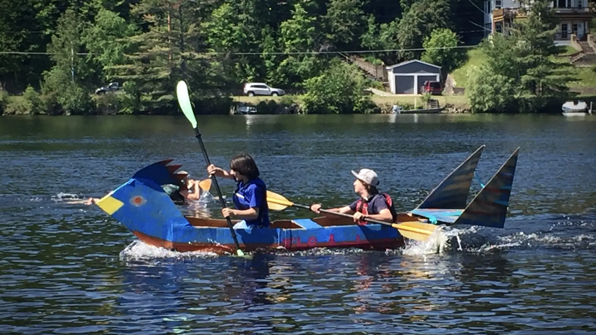 children in a handmade and hand painted cardboard boat on lake flower
