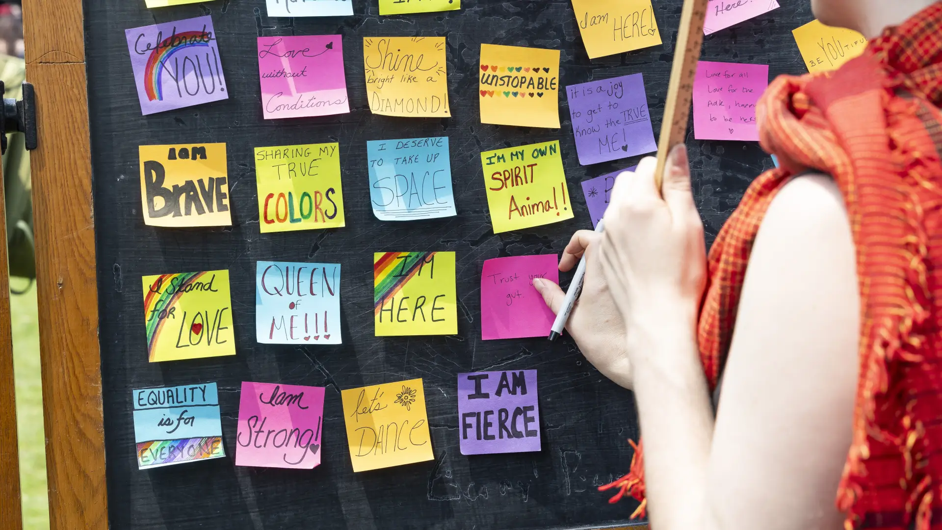 Sticky notes of affirmations hang on a chalkboard