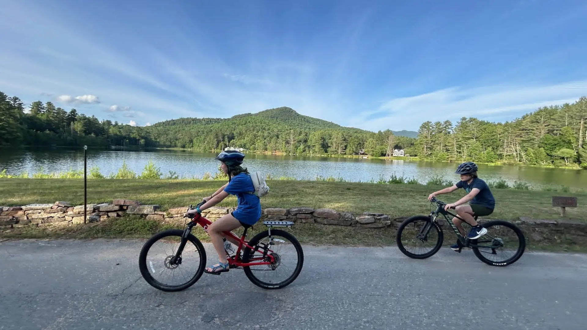 two road cyclists with pond in the background 