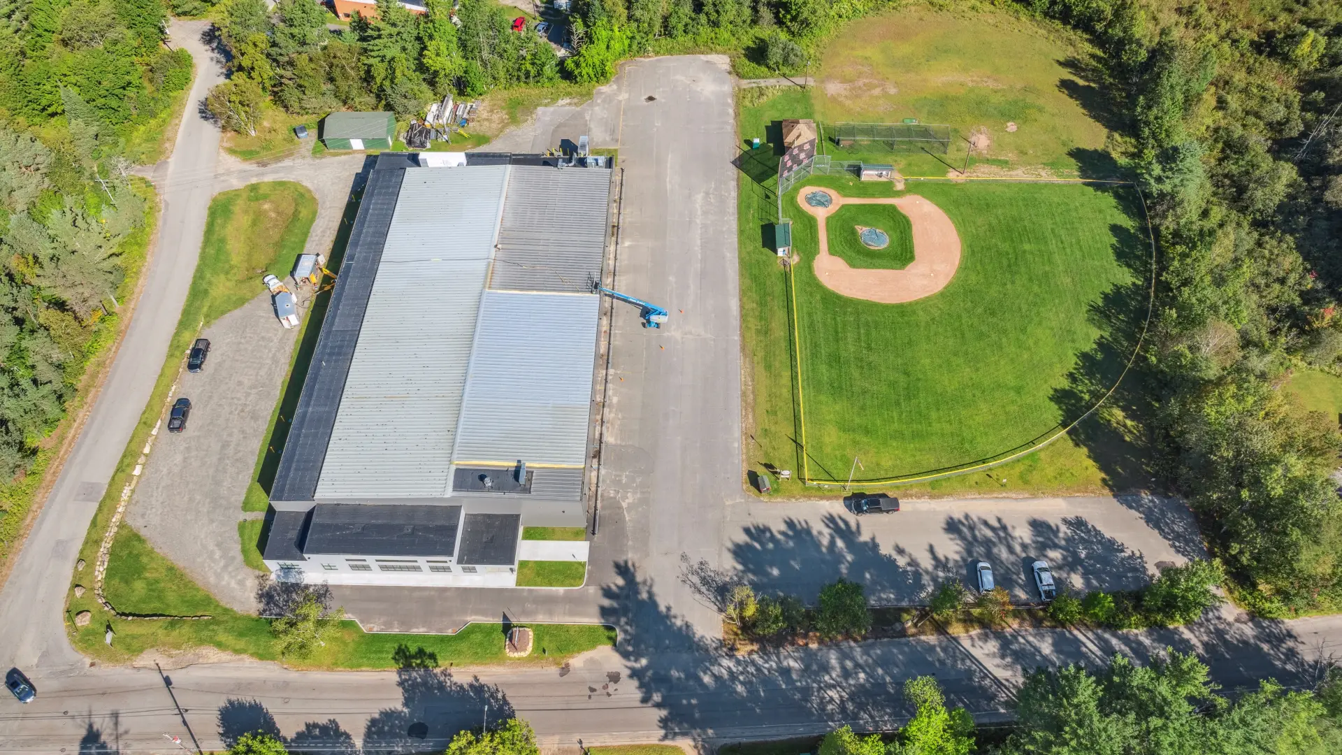 An aerial view of the top of the Saranac Lake Civic Center next to a baseball diamond.