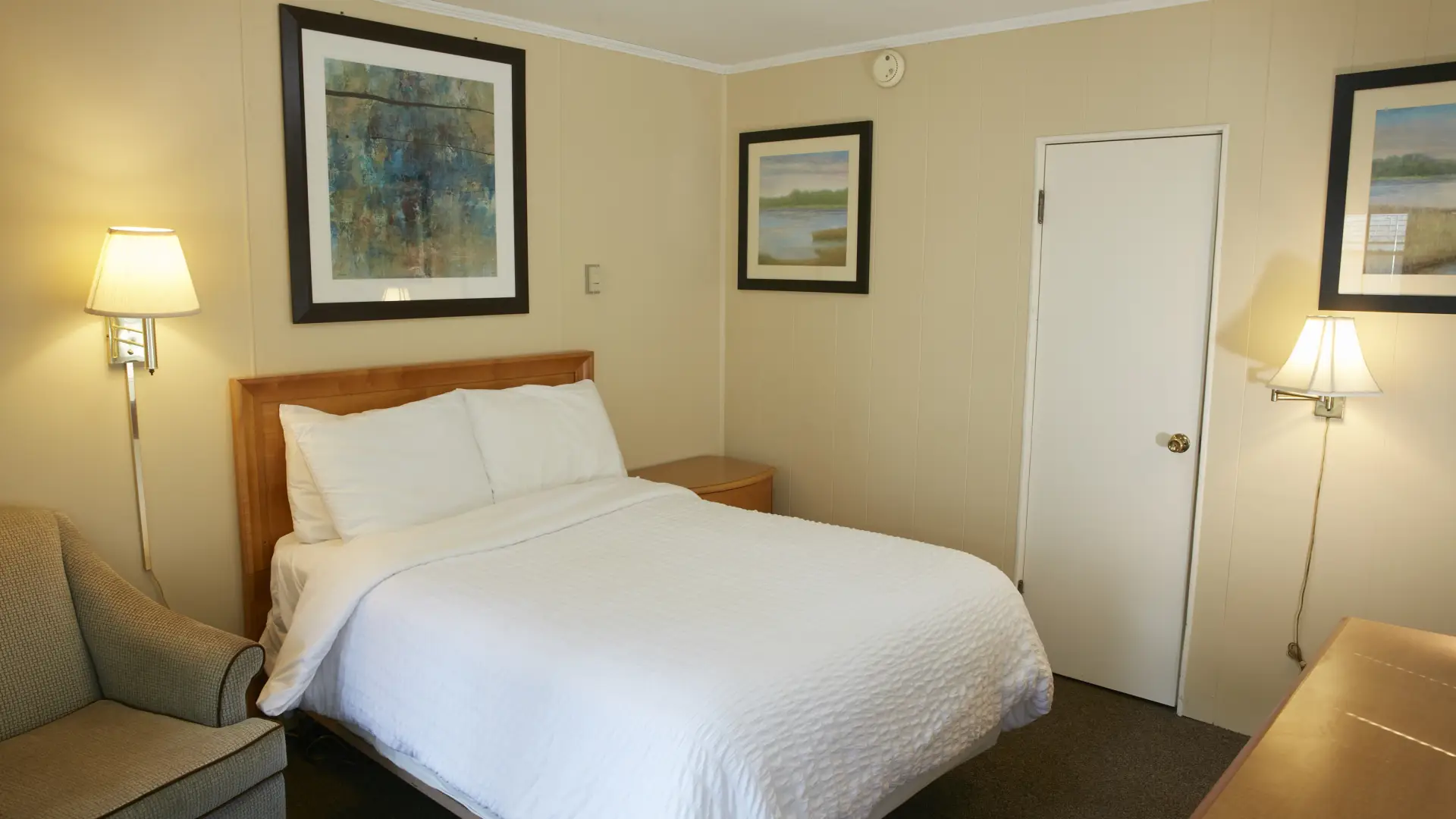 Plush white linens on a queen bed in a yellow walled room at The Ashley.