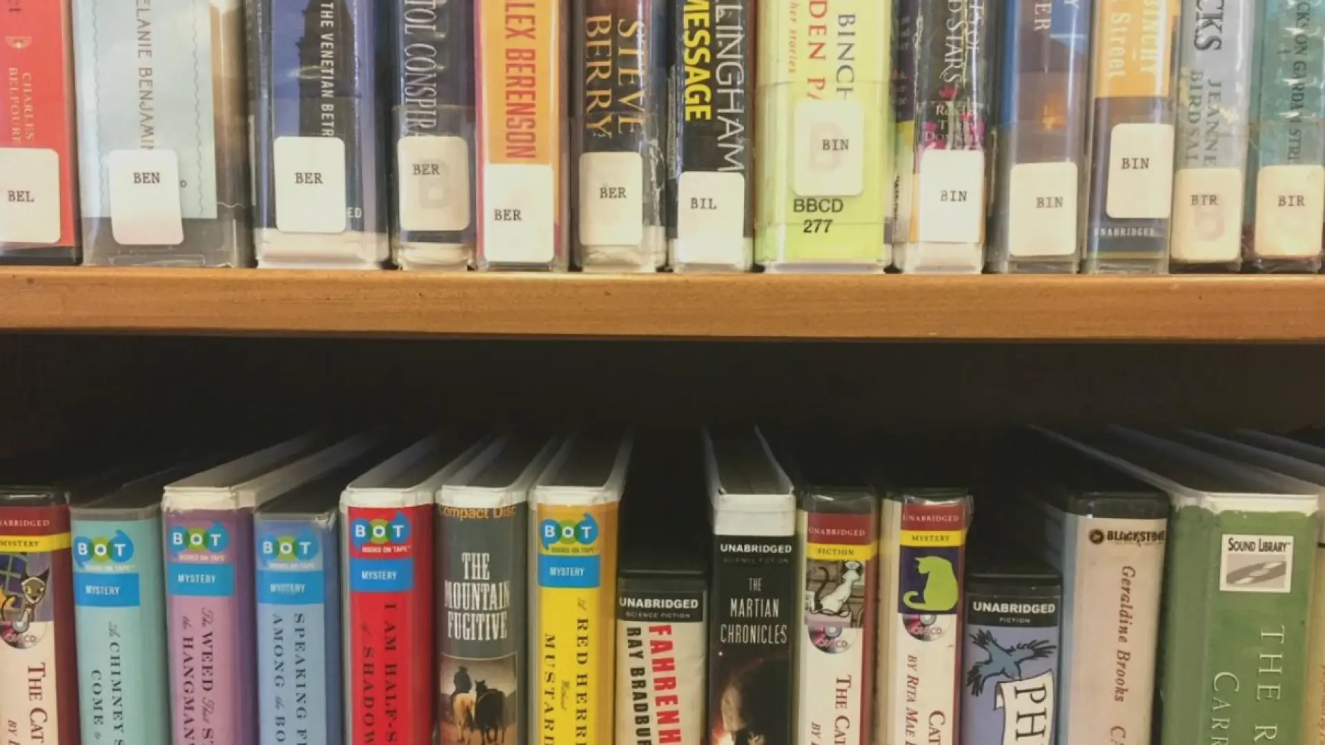 Books arranged on a shelf with their library stickers on the spine