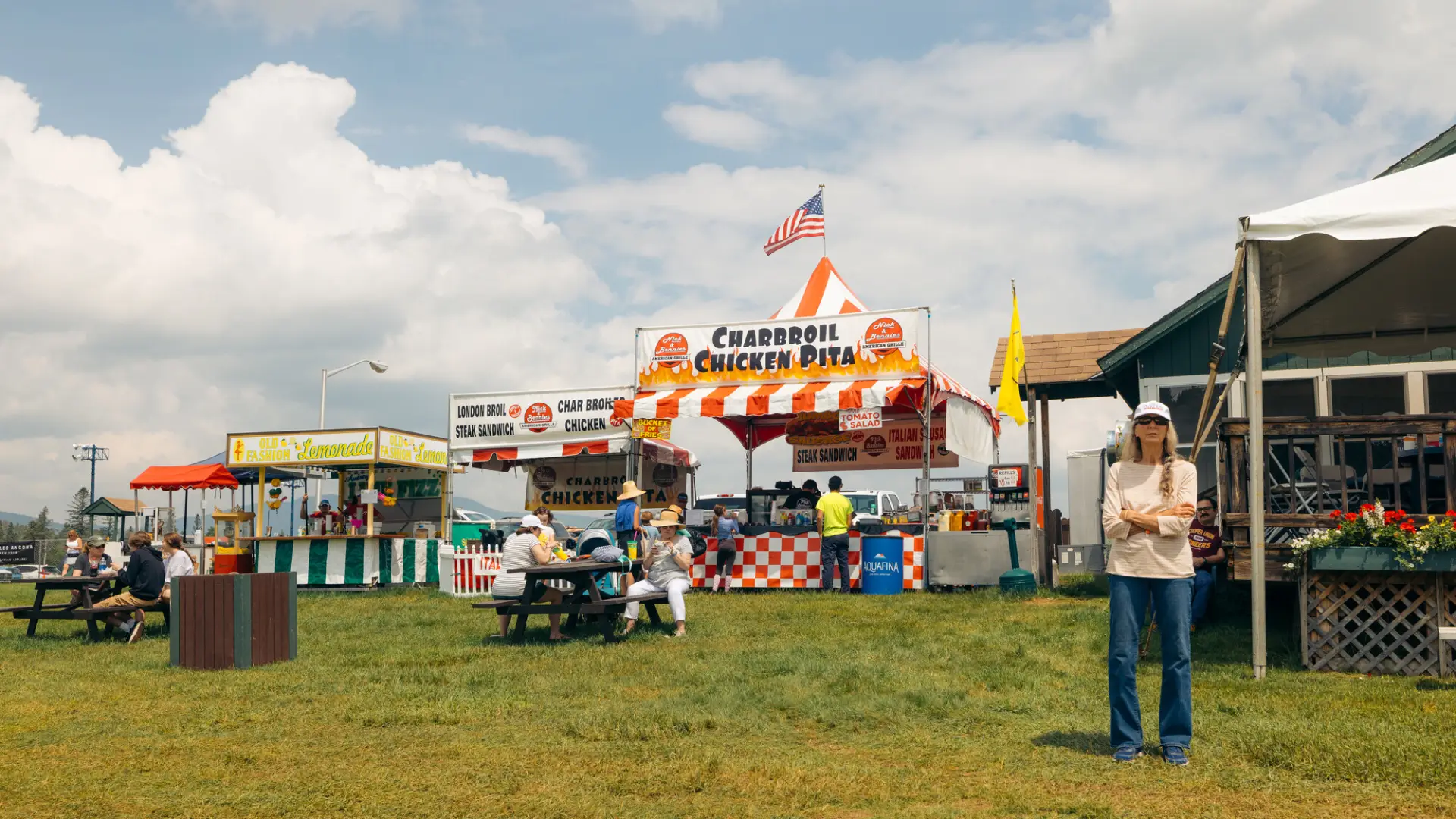 A woman contemplates her options by the vendors while families sit at picnic tables.