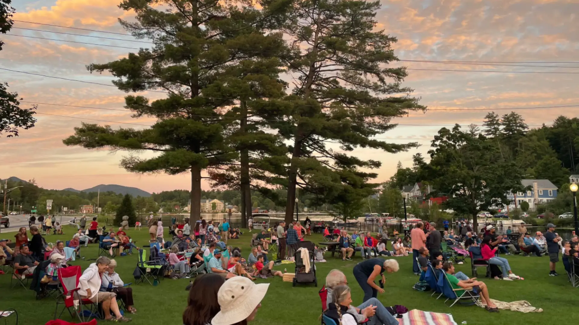 outdoor music concert with lake in the background as the sun goes down 